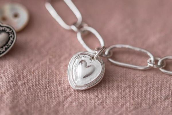 A handmade sterling silver bracelet with a heart-shaped button charm—filled with love, memory, and nostalgic charm from the Once Upon a Button collection.