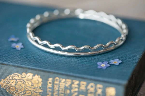 Handmade sterling silver High Tide Wave Bangle with flowing curves and optional initial charm—crafted with care and inspired by Norfolk’s wild coastline.