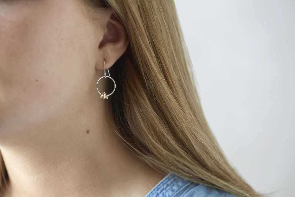gold bee hoop drop earrings worn by woman with long hair