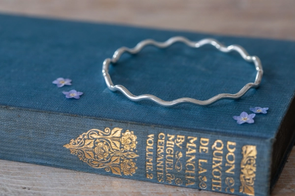 Handmade sterling silver Gentle Tide Wave Bangle with flowing curves and optional charm—elegant and calming, inspired by Norfolk’s gentlest seas.