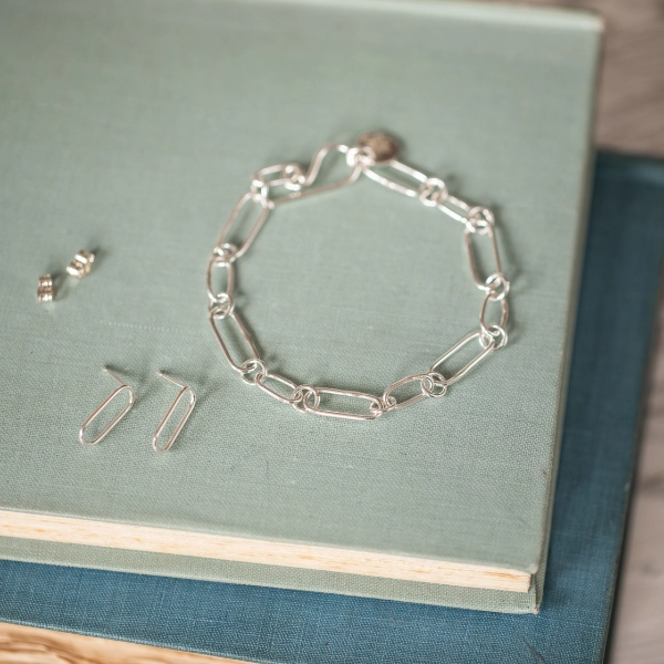 silver paperclip style bracelet and matching earrings resting on 2 vintage books