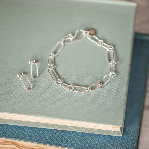 silver paperclip style bracelet and matching earrings resting on 2 vintage books