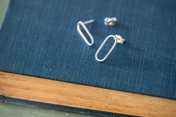silver paperclip style stud earrings resting on a vintage blue book