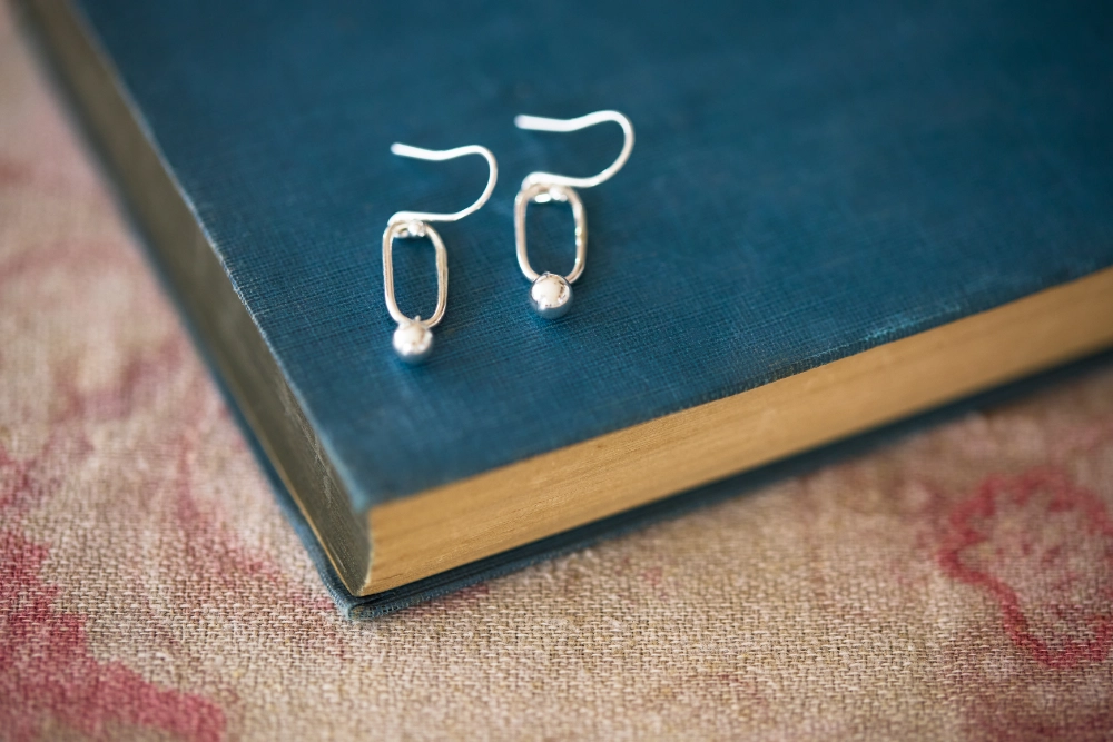 Handmade in Norfolk, these sterling silver paperclip drop earrings pair a simple elongated link with a polished silver ball for easy everyday wear.