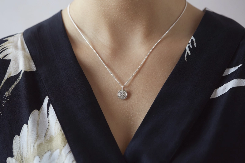 Silver button necklace worn on woman with v neck black dress