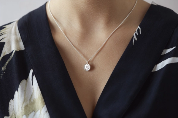 Silver button necklace worn on woman with v neck black dress