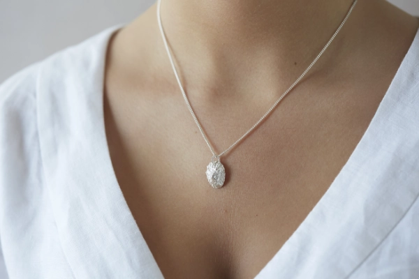 silver limpet shell necklace worn on model wearing white linen v neck dress