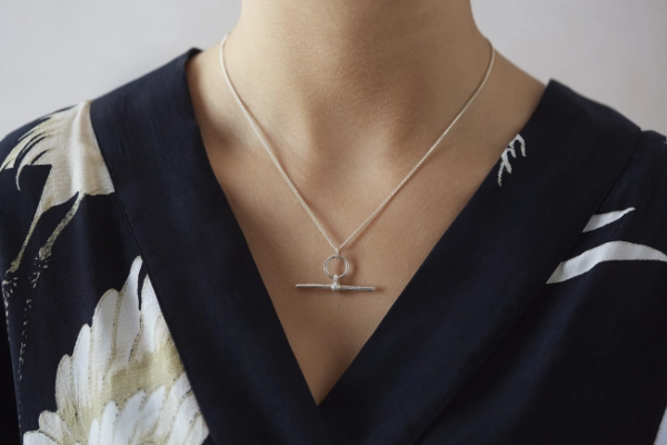 silver t bar necklace worn by model in a v neck black dress