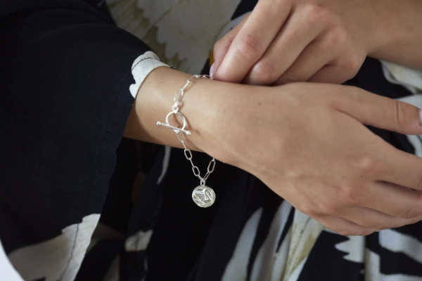 silver swan button bracelet worn by model wearing a black dress