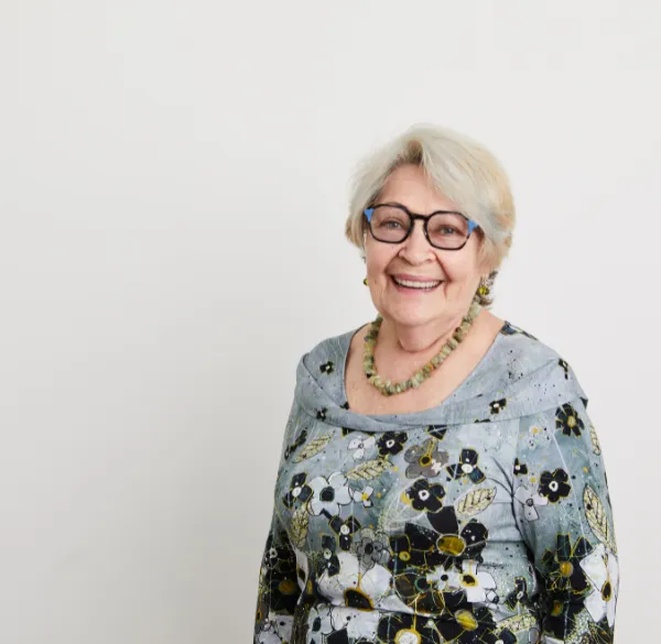 An elderly woman in glasses and a floral dress, contemplating her options for Full Mouth Dental Implants to enhance her smile
