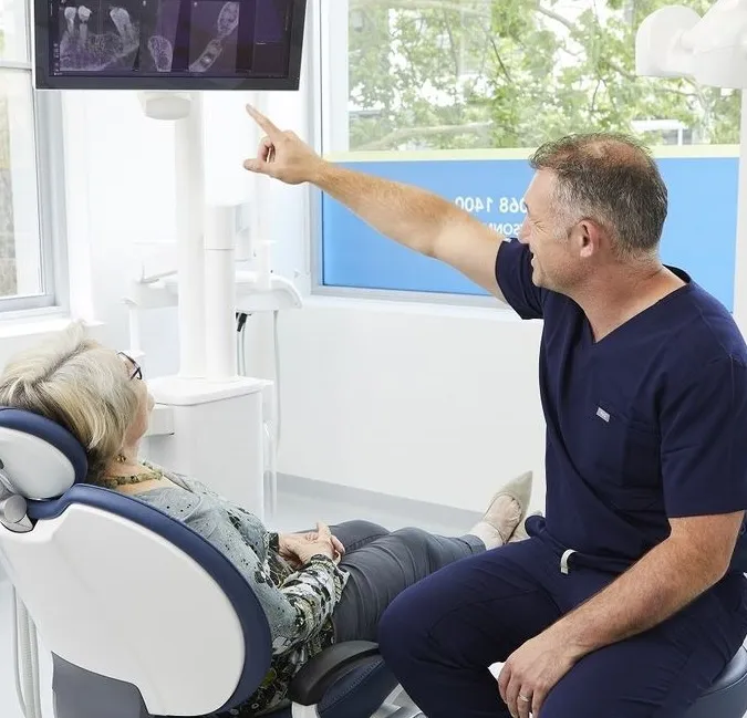 Dr. Daniel Adamo discusses the All On 4 success rate with a woman sitting in a dental chair during consultation