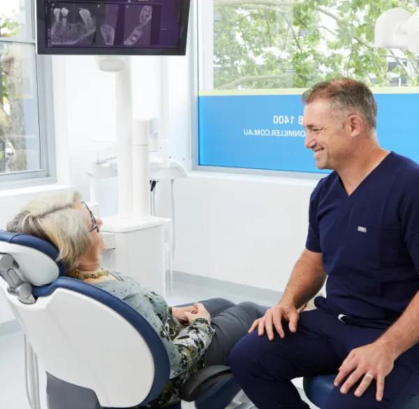 Dr. Daniel Adamo discusses the All On 4 success rate with a woman sitting in a dental chair during consultation