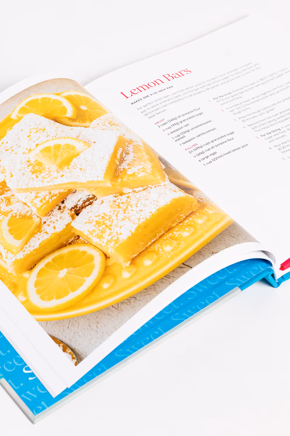 Cookbook titled "Sweet" by Beth Baumgartner showing a lemon bars recipe page with an image of powdered sugar-topped lemon bars garnished with lemon slices on a yellow plate.