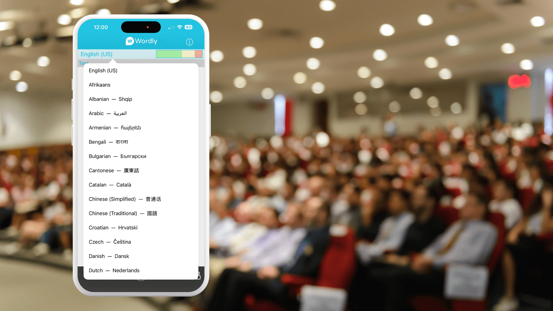 A smartphone screen displaying Wordly, shown against the blurred background of a large international conference audience