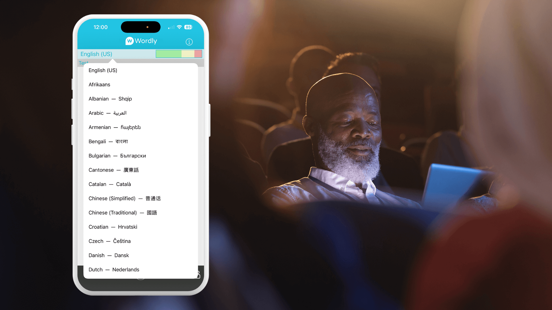 A conference attendee using a smartphone to view the Wordly app interface showing a list of available translation languages. The attendee is seated in a conference room.