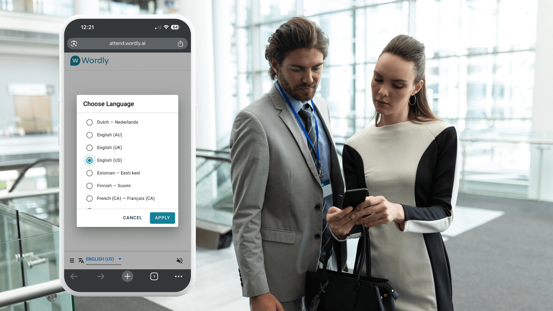 Two professionals stand together reviewing a mobile phone displaying Wordly, which shows a list of available languages for real-time translation and captions