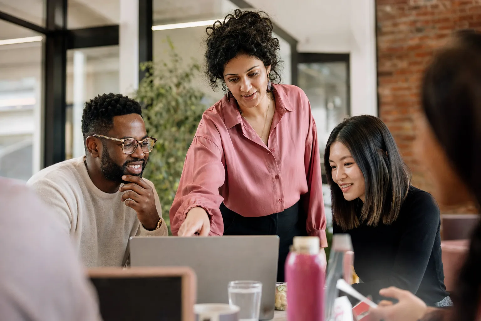 A facilitator leading an AI lunch-and-learn as colleagues lean in over laptops
