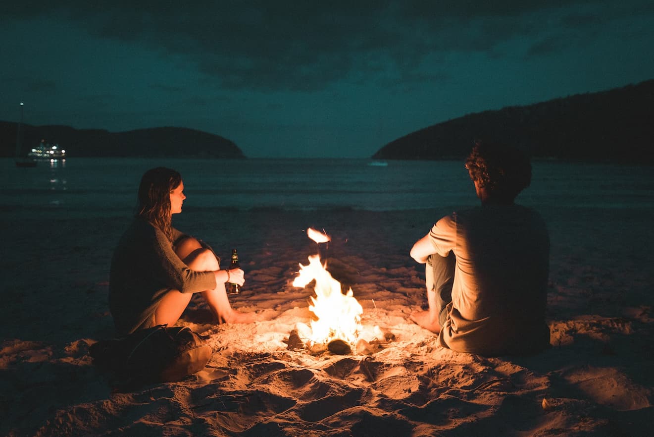 man-and-woman-with-bone-fire-sitting-on-seashore