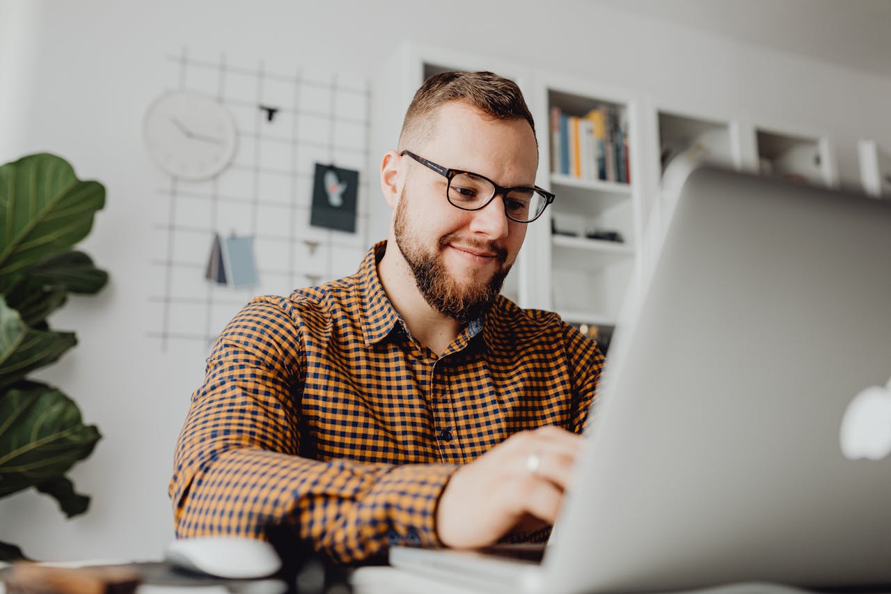 a-man-in-a-checkered-long-sleeves-using-a-laptop