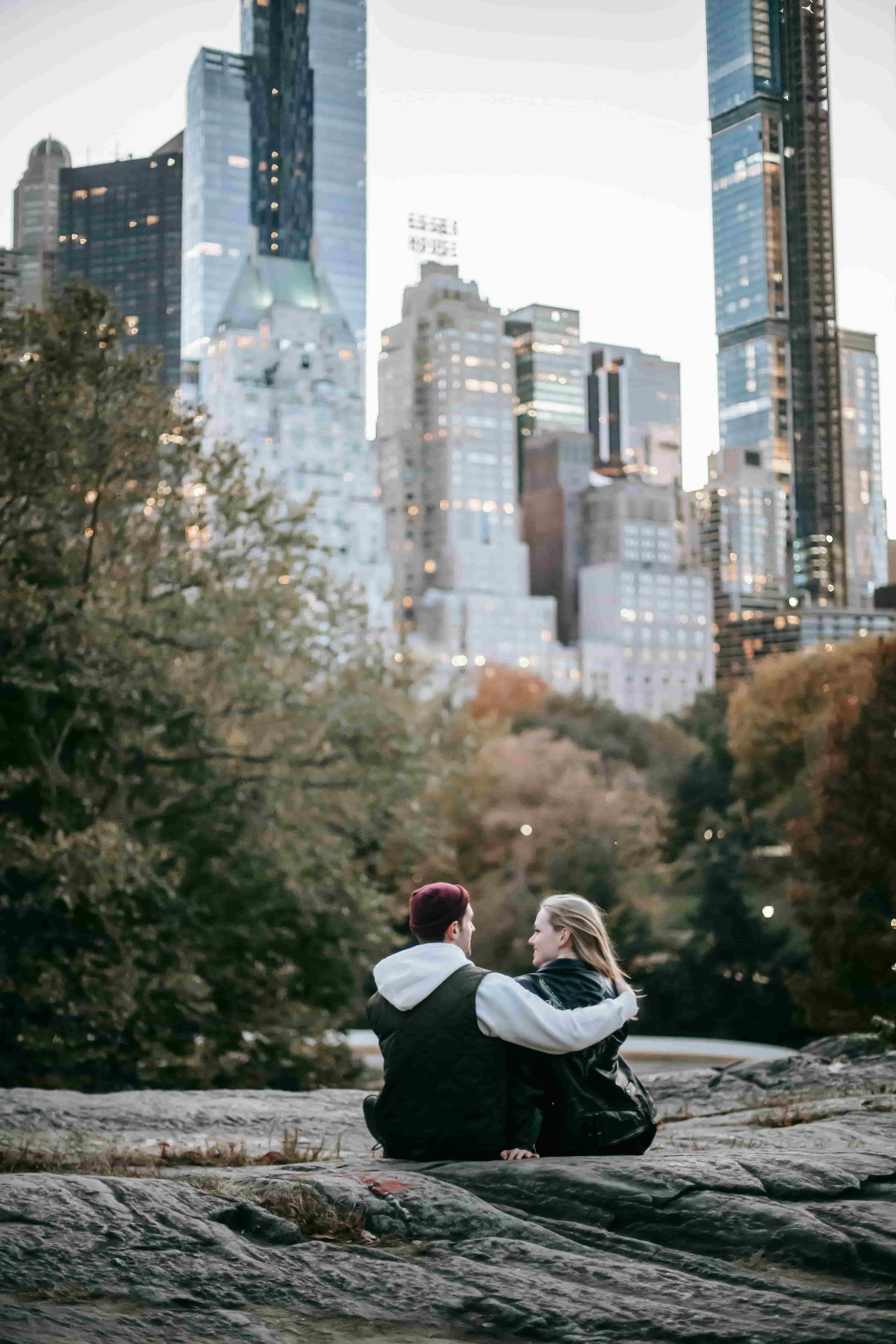 anonymous couples hugging while sitting on the stone in the park
