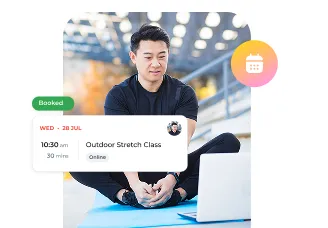 Man sitting on exercise mat looking at laptop with Outdoor Stretch Class booking details displayed.