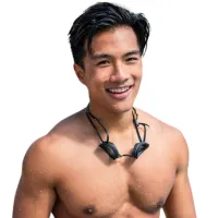 Smiling muscular young man with wet hair and wireless earphones around neck against white background.