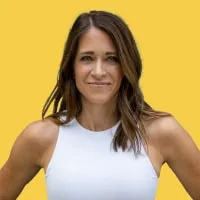 Smiling woman with shoulder-length brown hair wearing a white sleeveless top against a yellow background.