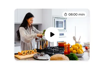 Woman cooking in a bright kitchen with fresh vegetables and lemons on the counter, preparing a meal in a large pot.