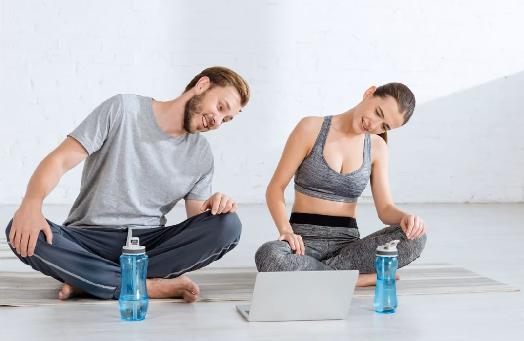 Couple using a laptop for a home workout session with fitness apps and workout apps.