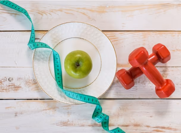 image is showing us a fruit on the plate and a dumbbell in side