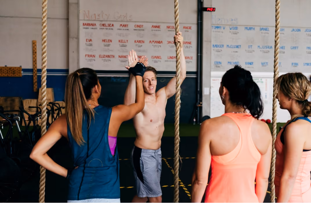 two gym friends shaking hands while one on rope of the gym