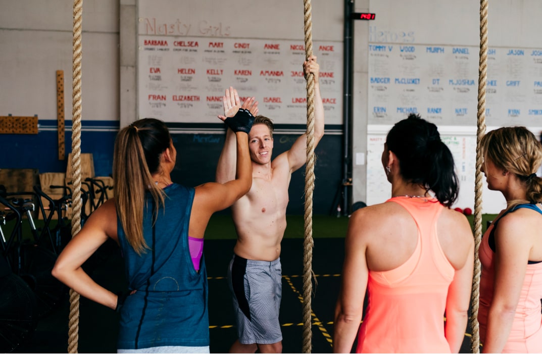 two gym friends shaking hands while one  on rope of the gym