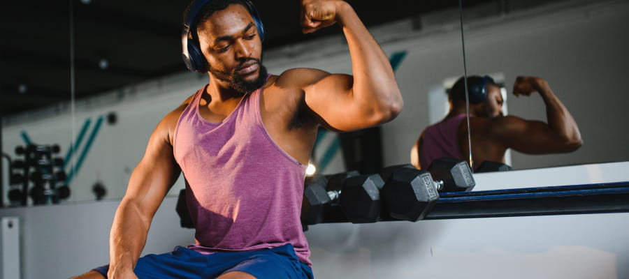 a body builder posing with headphones in ear
