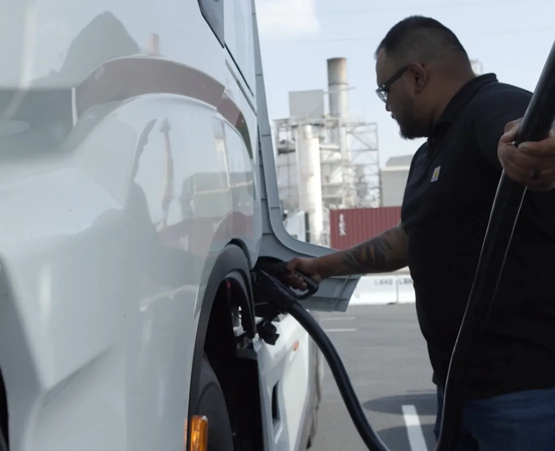 A man plugging in an electric semi truck to charge