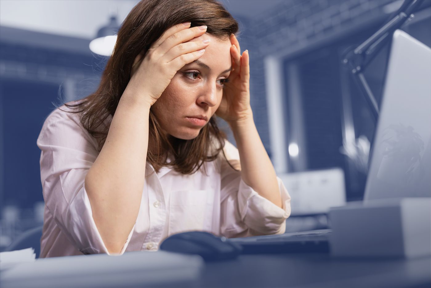 An overwhelmed HR professional at her desk, head in her hands