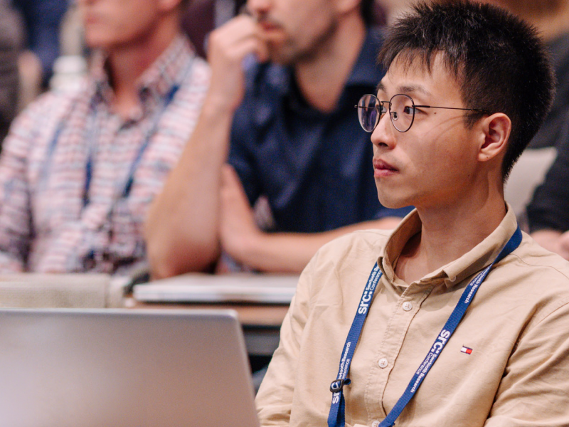 Man with glasses attentively listening in a conference room.