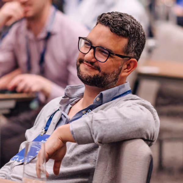 Man smiling and sitting in a chair at the conference.