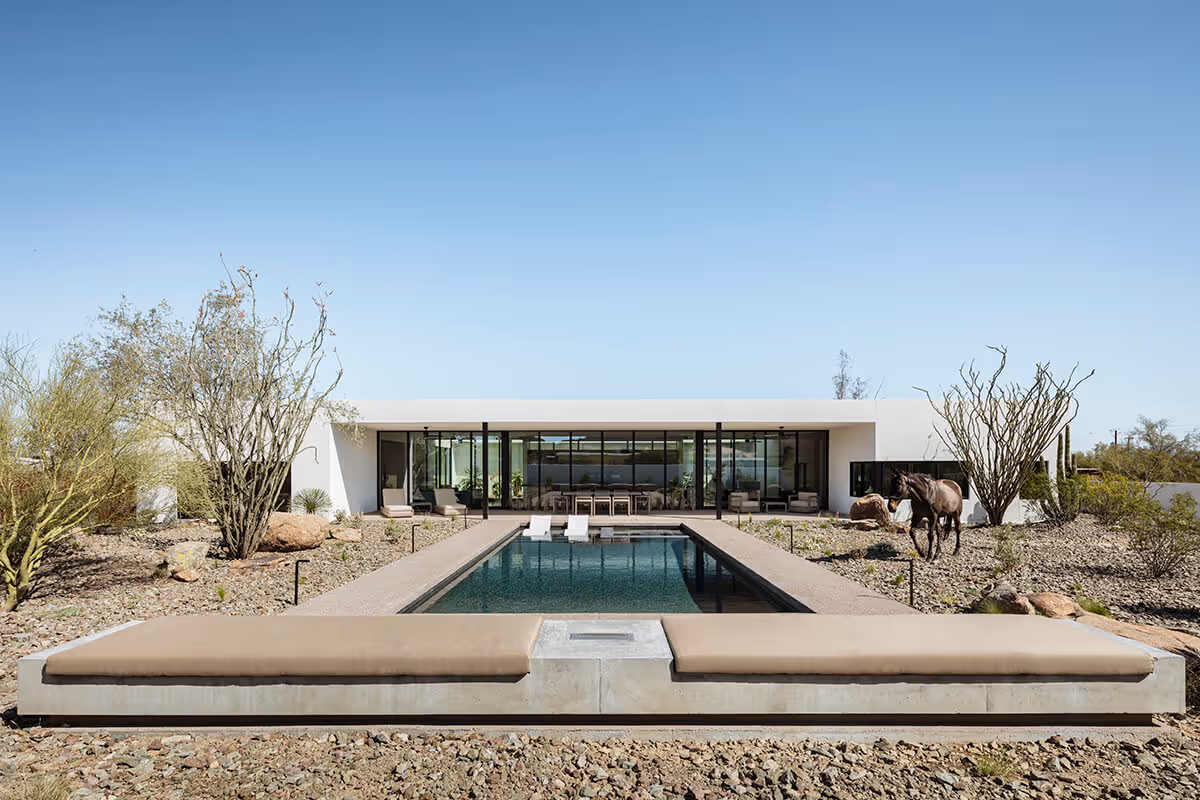 bench with a firepit next to a pool in the desert in a modern desert house by The Ranch Mine