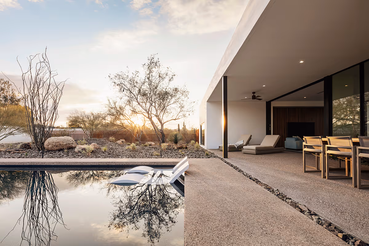sunset view of covered patio next to a pool in a modern desert house by The Ranch Mine