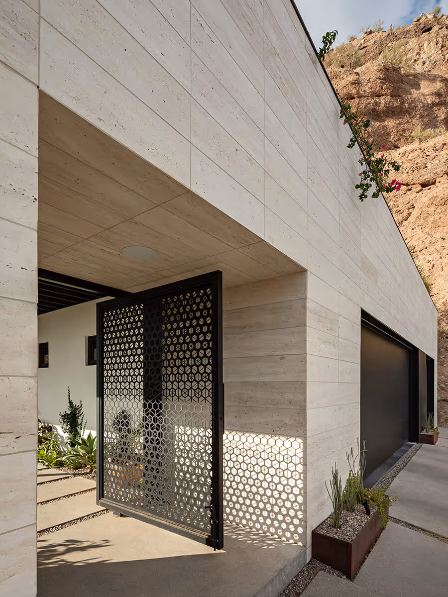 Custom entry gate in a limestone facade at a home renovation and addition transforming a Spanish Colonial Revival house into a modern mountainside home in Phoenix by The Ranch Mine