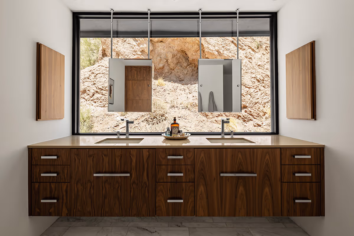 Bathroom with window behind the vanity and floating mirrors in front of a mountain view by The Ranch Mine