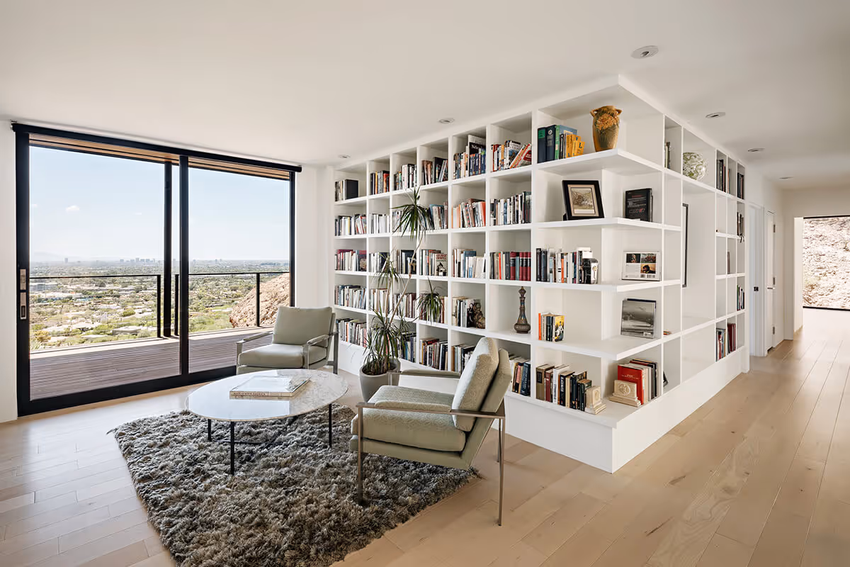 Wrap around bookshelf with a view out to the Phoenix skyline at a modern home in Phoenix by The Ranch Mine