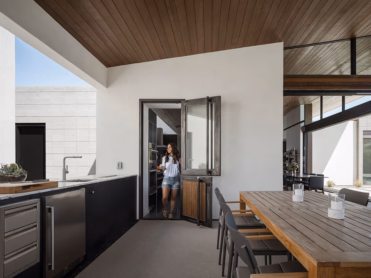 Modern steel and wood dutch door with outdoor kitchen on covered patio at a modern home in Phoenix by The Ranch Mine