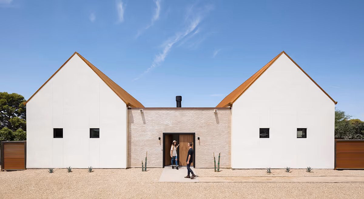 Exterior with white stucco, adobe colored brick and rusted steel at a southwest modern house by The Ranch Mine