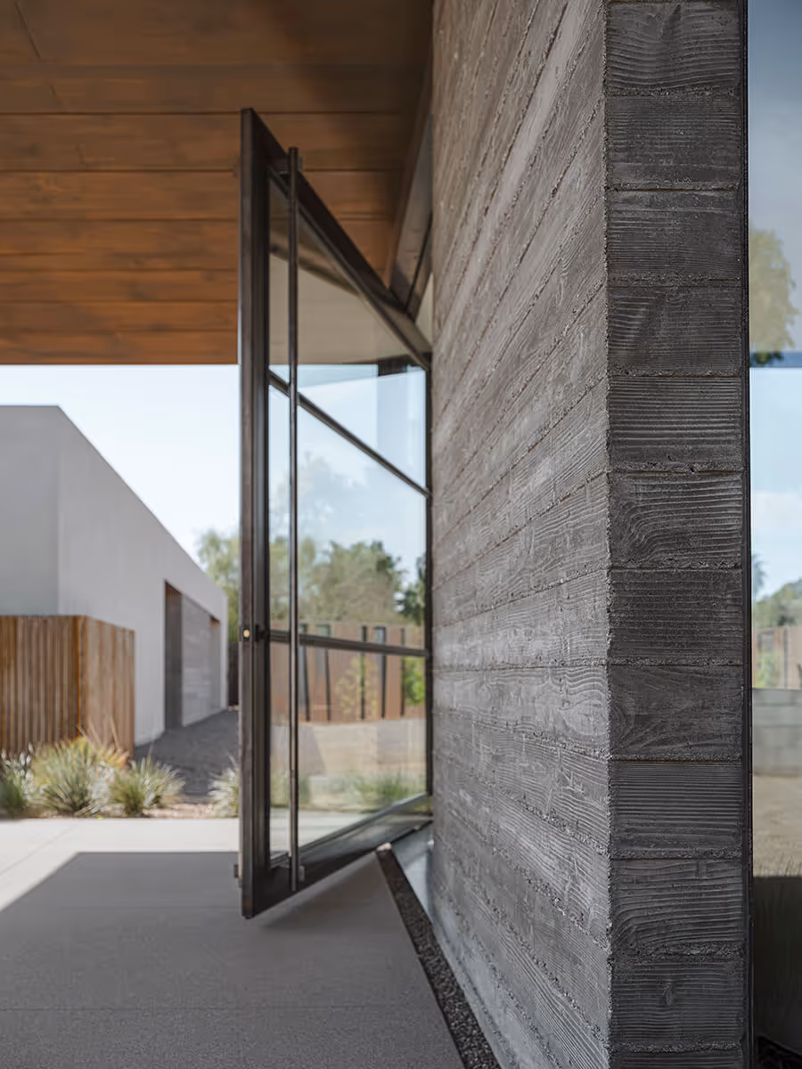 Huge steel and glass pivot door detail with boardformed concrete wall on a casita in Phoenix by The Ranch Mine