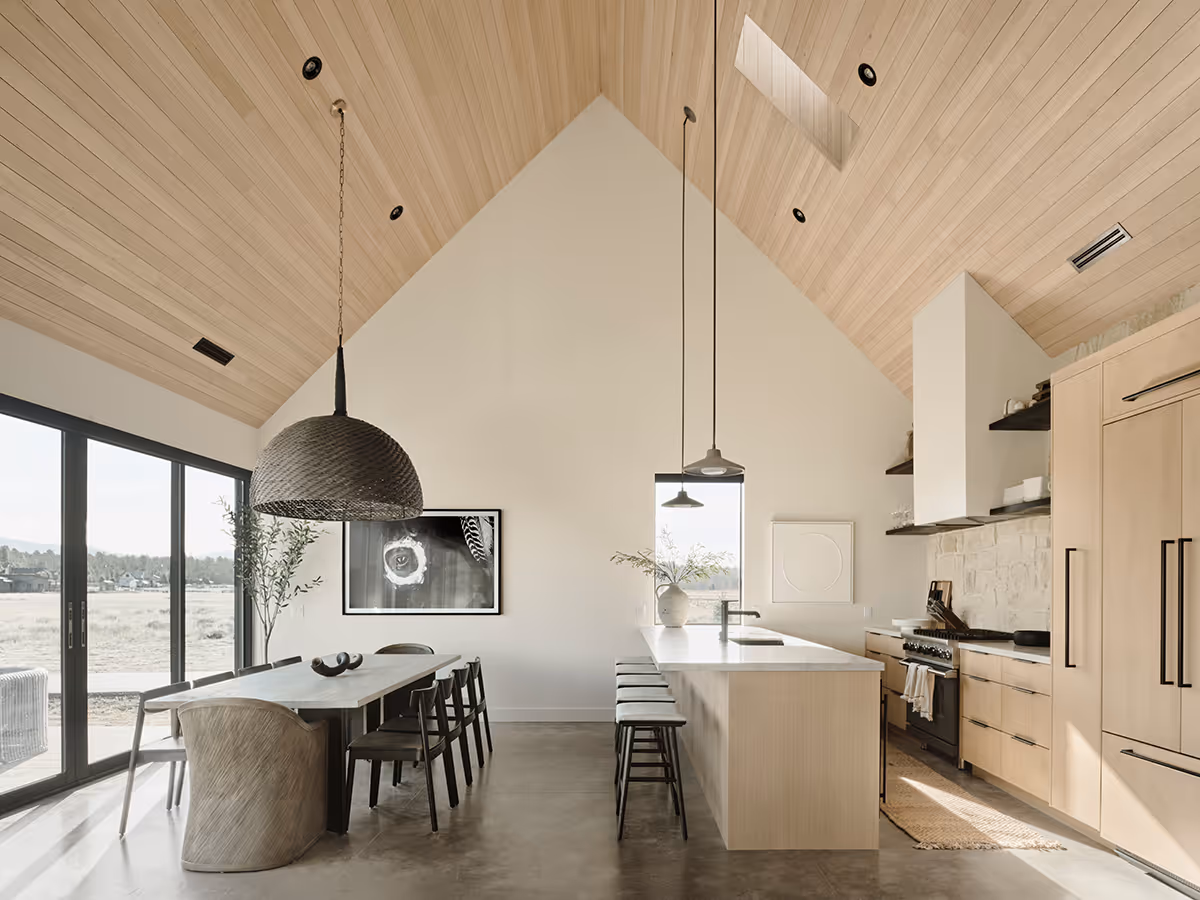 Dining room and kitchen with a vaulted wood ceiling at a modern Scandinavian house in Flagstaff, Arizona by The Ranch Mine