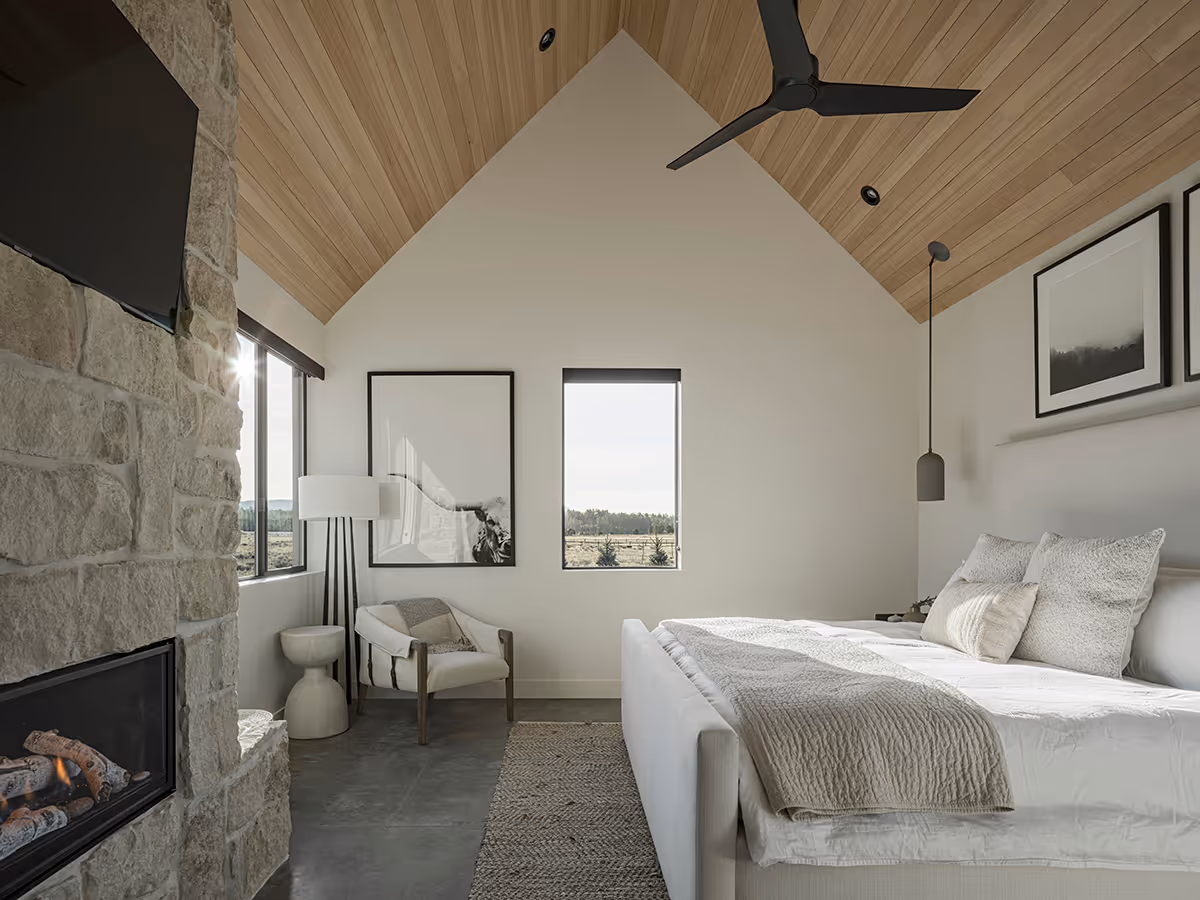 Primary suite with a vaulted wood ceiling and stone fireplace at a modern Scandinavian house in Flagstaff, Arizona by The Ranch Mine