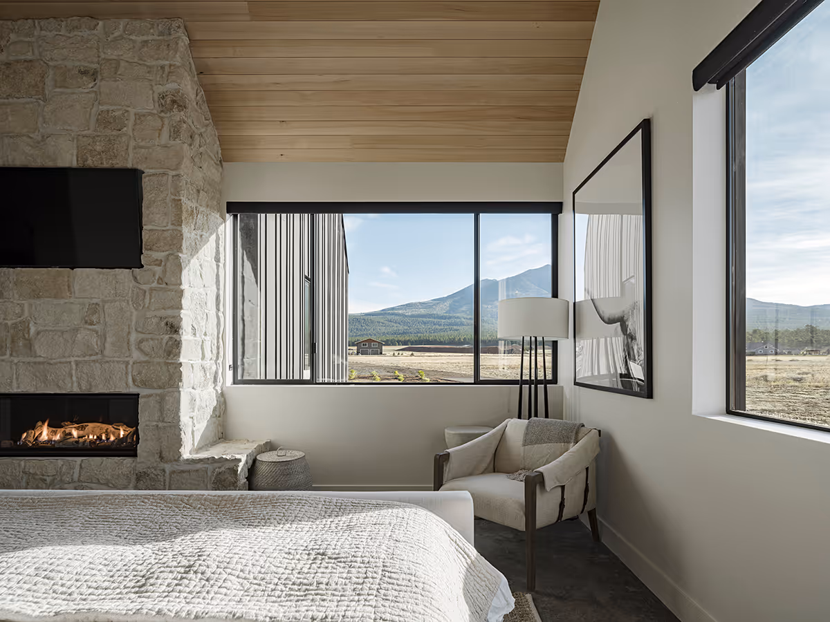 Primary suite with a vaulted wood ceiling and stone fireplace at a modern Scandinavian house in Flagstaff, Arizona by The Ranch Mine