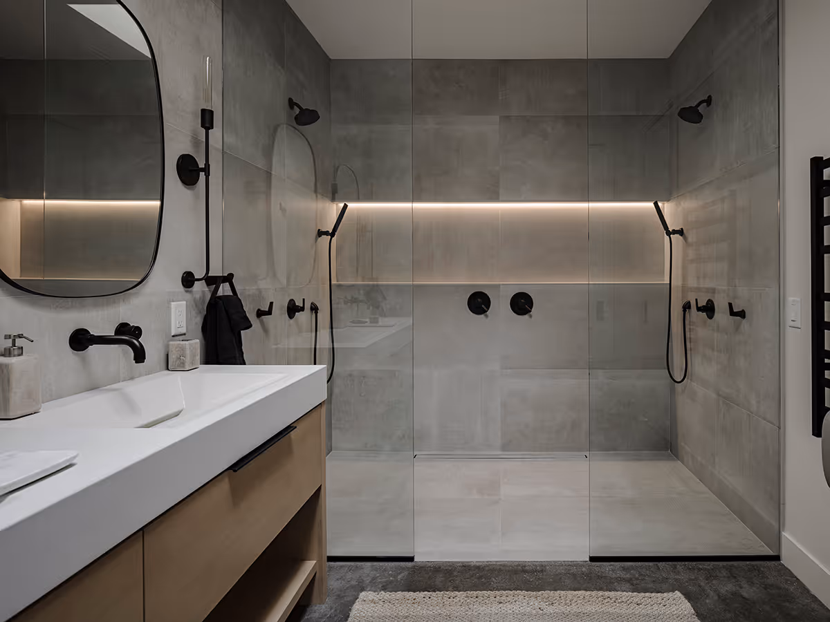 Skylit cozy bathroom with an LED lit niche in the shower at a modern Scandinavian black exterior house with gabled roofs in Flagstaff, Arizona by The Ranch Mine