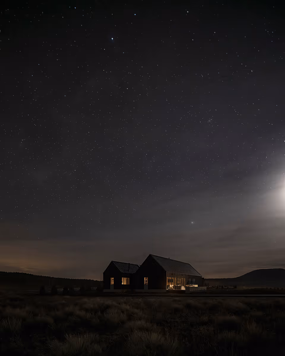 Modern Scandinavian black exterior house with gabled roofs in Flagstaff, Arizona by The Ranch Mine at night with the stars